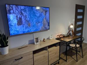 a large flat screen tv on a wall with a desk at Apartament ,, Sen i Kawa'' - komfortowy nocleg w sercu aglomeracji in Bytom