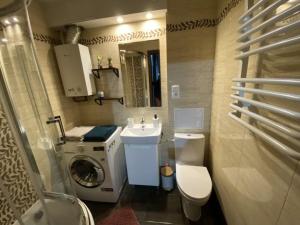 une petite salle de bains avec un lave-linge et un lavabo dans l'établissement Apartament ,, Sen i Kawa'' - komfortowy nocleg w sercu aglomeracji, à Bytom