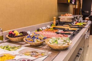 uma linha de buffet com muitos tipos diferentes de alimentos em Lion's Garden Hotel em Budapeste