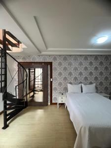 Un dormitorio con una cama blanca y una escalera en Pousada Cida Baiana Casarão, en Florianópolis