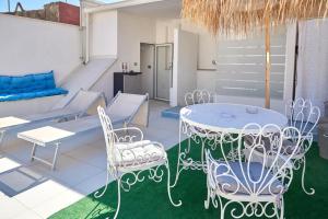 a patio with white chairs and a table and chairs at Madama B&B in Gaeta