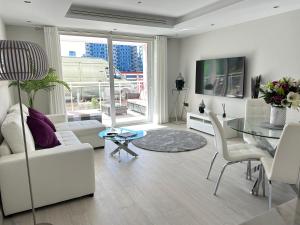 a living room with white furniture and a glass table at Marina Club - Luxury Apartment in Ocean Village with Parking in Gibraltar