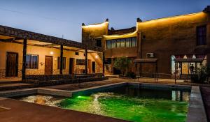 a house with a swimming pool in front of a building at Palais Ksar Lamane in Aït Ben Haddou