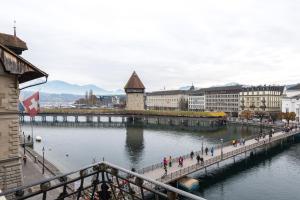 a group of people walking along a bridge over a river at Altstadt Hotel Magic Luzern in Luzern