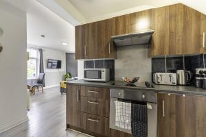 kuchnia z drewnianymi szafkami i kuchenką mikrofalową w obiekcie Comfy Stay 1 Bedroom Apartment w mieście Rugby