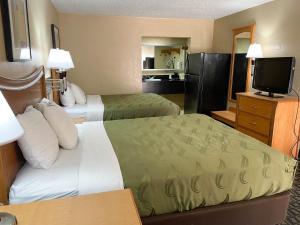 a hotel room with two beds and a flat screen tv at Studio 6 Suites North Richland Hills TX in North Richland Hills