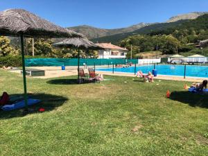 a group of people laying on the grass near a swimming pool at NovaCand in Candelario