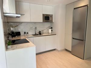 a kitchen with white cabinets and a stainless steel refrigerator at Marina Club - Luxury Apartment in Ocean Village with Parking in Gibraltar
