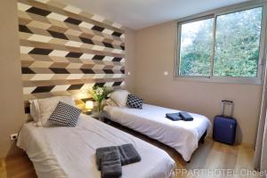 a room with two beds and a window at Appart hotel Cholet Carteron in Cholet