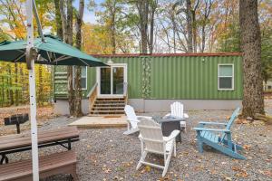 a green cabin with chairs and a table and an umbrella at Camptel Poconos in Albrightsville