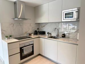 a kitchen with white cabinets and a sink and a microwave at Marina Club - Luxury Apartment in Ocean Village in Gibraltar