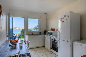 a kitchen with a table and a white refrigerator at Villa Les Pieds Dans L'eau in Loctudy