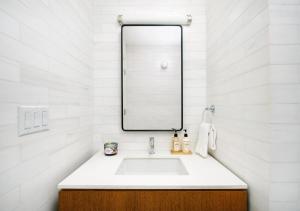 La salle de bains blanche est pourvue d'un lavabo et d'un miroir. dans l'établissement Modern Studio Apartment At East Side, à New York