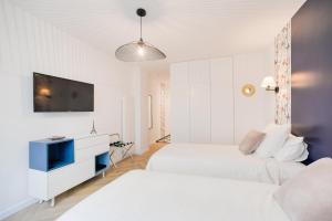 a white bedroom with two beds and a tv at Studio "Café Papillon"-Paris 15 in Paris