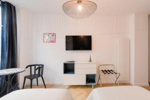 a living room with a white cabinet and a tv at Studio "Café Papillon"-Paris 15 in Paris