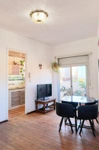 ein Wohnzimmer mit einem Tisch, Stühlen und einem TV in der Unterkunft Apartamento esq Rambla y centrico in Montevideo