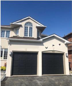 a house with two garage doors in front of it at Riaz's Peaceful Mississauga Home in Mississauga