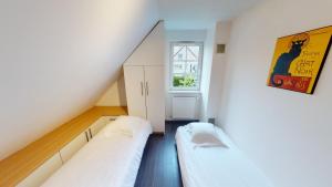 two beds in a small room with a window at Ô calme Maison familiale - Wickerschwihr in Wickerschwihr