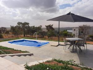 einen Tisch und einen Sonnenschirm neben einem Pool in der Unterkunft Rancho Teixeira in Alexânia