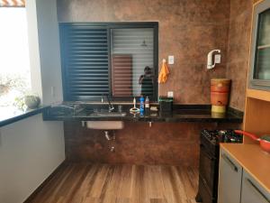 eine Küche mit Spüle und eine Person im Spiegel in der Unterkunft Rancho Teixeira in Alexânia