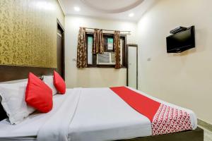 a bedroom with a bed with red pillows and a television at OYO Flagship R.S. RESIDENCY in New Delhi