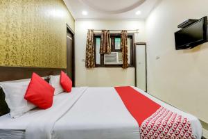 a bedroom with a bed with red pillows and a tv at OYO Flagship R.S. RESIDENCY in New Delhi