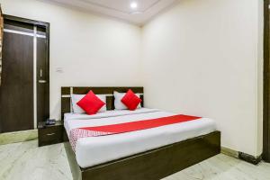 - une chambre avec un grand lit et des oreillers rouges dans l'établissement OYO Flagship R.S. RESIDENCY, à New Delhi