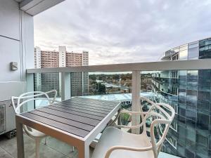 a balcony with a wooden table and chairs on a balcony at Close To Mel Uni 2br 2ba Parking Balconywifigy in Melbourne
