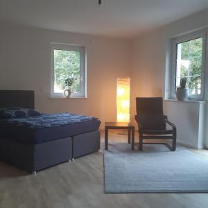 a bedroom with a bed and a chair and a lamp at Ferienwohnung in Hohen Neuendorf bei Berlin, Zentral gelegen in Hohen Neuendorf