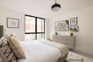a white bedroom with a bed and a window at The Wembley Place - Stunning 1BDR Flat in London