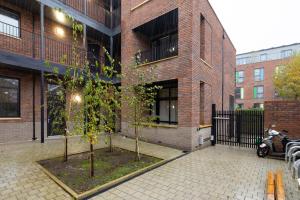 a brick building with two trees in front of it at The Wembley Place - Stunning 1BDR Flat in London