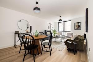 a dining room and living room with a table and chairs at The Wembley Place - Stunning 1BDR Flat in London