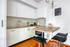 a kitchen with white cabinets and a wooden counter top at Athena's South Apartment in Athens