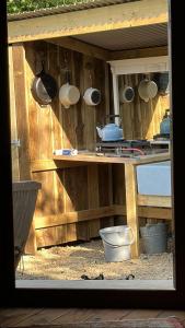 卡迪根的住宿－The Yurt @ Penbanc Pasture，厨房配有挂在木墙上的锅碗瓢盆