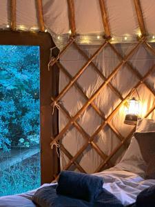卡迪根的住宿－The Yurt @ Penbanc Pasture，帐篷内的一张床位,墙上有灯