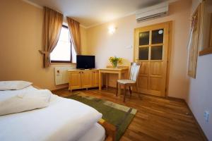 a bedroom with a bed and a desk with a television at Hotel Karpatsky Dvor in Lozorno