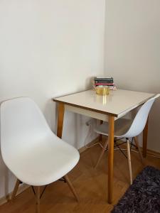 a table and two white chairs in a room at Little Duomo in Košice