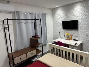 ein Schlafzimmer mit einem Kinderbett, einem Schreibtisch und einem TV in der Unterkunft Moradas Desterro, próximo ao aeroporto 05 in Florianópolis