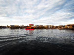 a boat in a body of water with houses at Q'OTA TAYPY LODGE in Puno