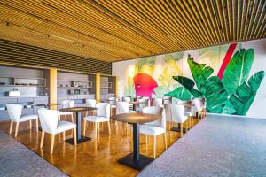 a restaurant with tables and white chairs and a mural at Resort Cordial Santa Águeda & Perchel Beach Club in La Playa de Arguineguín