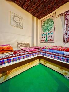Duas camas num quarto com piso verde em Spiti Horizon Homestay em Kaza