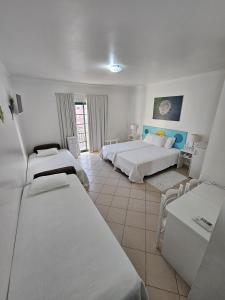 a hotel room with two beds and two tables at Hotel Adelaide in Faro