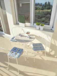 une table et des chaises blanches sur une terrasse couverte avec une fenêtre dans l'établissement Elia boutique apartment, à Thiva