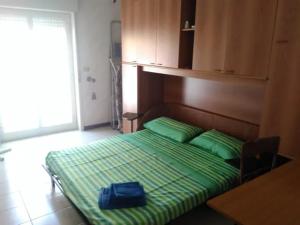 Una cama con sábanas verdes y una bolsa azul. en Grazioso appartamento vicino al mare en Giardini Naxos