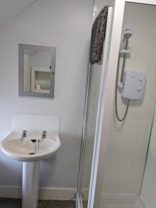 a white bathroom with a sink and a shower at Bennachie Lodge Hotel in Kemnay in Inverurie
