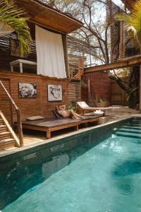 a woman laying on a bench next to a swimming pool at Eco Lodge Mancora in Máncora