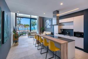 a kitchen with a bar with yellow chairs and a living room at Resort Cordial Santa Águeda & Perchel Beach Club in La Playa de Arguineguín