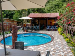 une piscine avec un parasol et une fontaine dans l'établissement Finca hotel Rios Claros, à San Luis