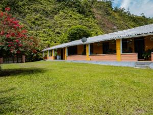 une maison jaune avec une cour d'herbe devant elle dans l'établissement Finca hotel Rios Claros, à San Luis
