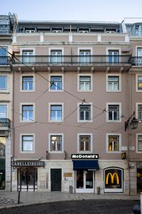 Um grande edifício cor-de-rosa com um letreiro do McDonald's. em Chiado Square Apartments | Lisbon Best Apartments em Lisboa